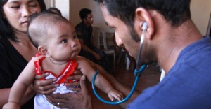 A member of the International Medical Corps checks an infants heart rate on Homonhon Island. (Credit: International Medical Corps)