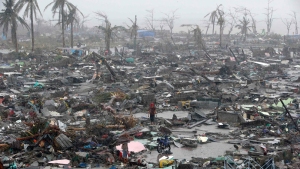 Survivors stand among the debris in Tacloban after Typhoon Haiyan. (Credit: Erik De Castro/Reuters)