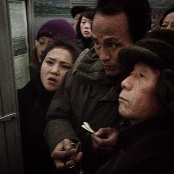 Commuters in Pyongyang gather around a hanging newspaper to learn the fate of Jang Song Thaek who was executed for being a counter-revolutionary traitor. Jang Song Thaek was married to the aunt of North Korea's supreme leader Kim Jong-un. (Credit: David Guttenfelder via Instagram)